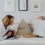 A mother interacting with her daughter hiding behind a pillow, enjoying quality time indoors.